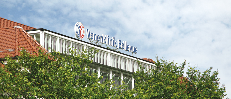 Der Schriftzug Venenklink Bellevue auf dem Dach der Venenklink vor sommelrich blauem Himmel.