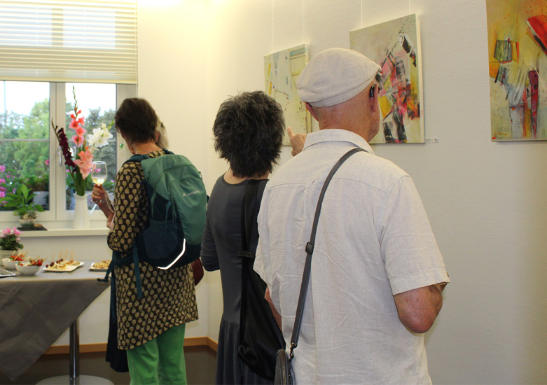 Besucher:innen betrachten Bilder der Künstlerin Francine Vonderhagen bei ihrer Vernissage in der Venenklink.